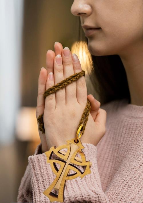 Trefoil Wooden Cross Necklace being held by a woman